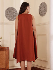 Back pose of a Woman wearing a rust color cotton linen dress with embroidery in an elegant interior