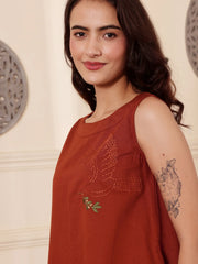 Left pose of a Woman wearing a rust color cotton linen dress with embroidery in an elegant interior