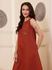 Left pose of a Woman wearing a rust color cotton linen dress with embroidery in an elegant interior setting