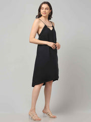 Side profile of a women wearing a black resort wear cocktail dress with noodle strap and black embellishment on neckline