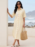 Woman in a cotton linen blend yellow shirt dress with embroidery holding a straw bag by a beach.