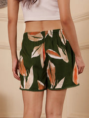Back pose of a Women wearing a green floral-print shorts with drawcord and tassels with a white top against a neutral background