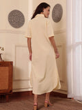 Back pose of a Woman wearing a light yellow cotton linen shirt dress with a floral design in a room with decorative elements.