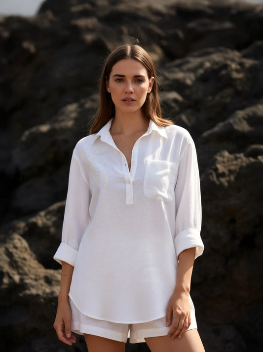 Woman wearing a white shirt and shorts standing against a dark, textured background