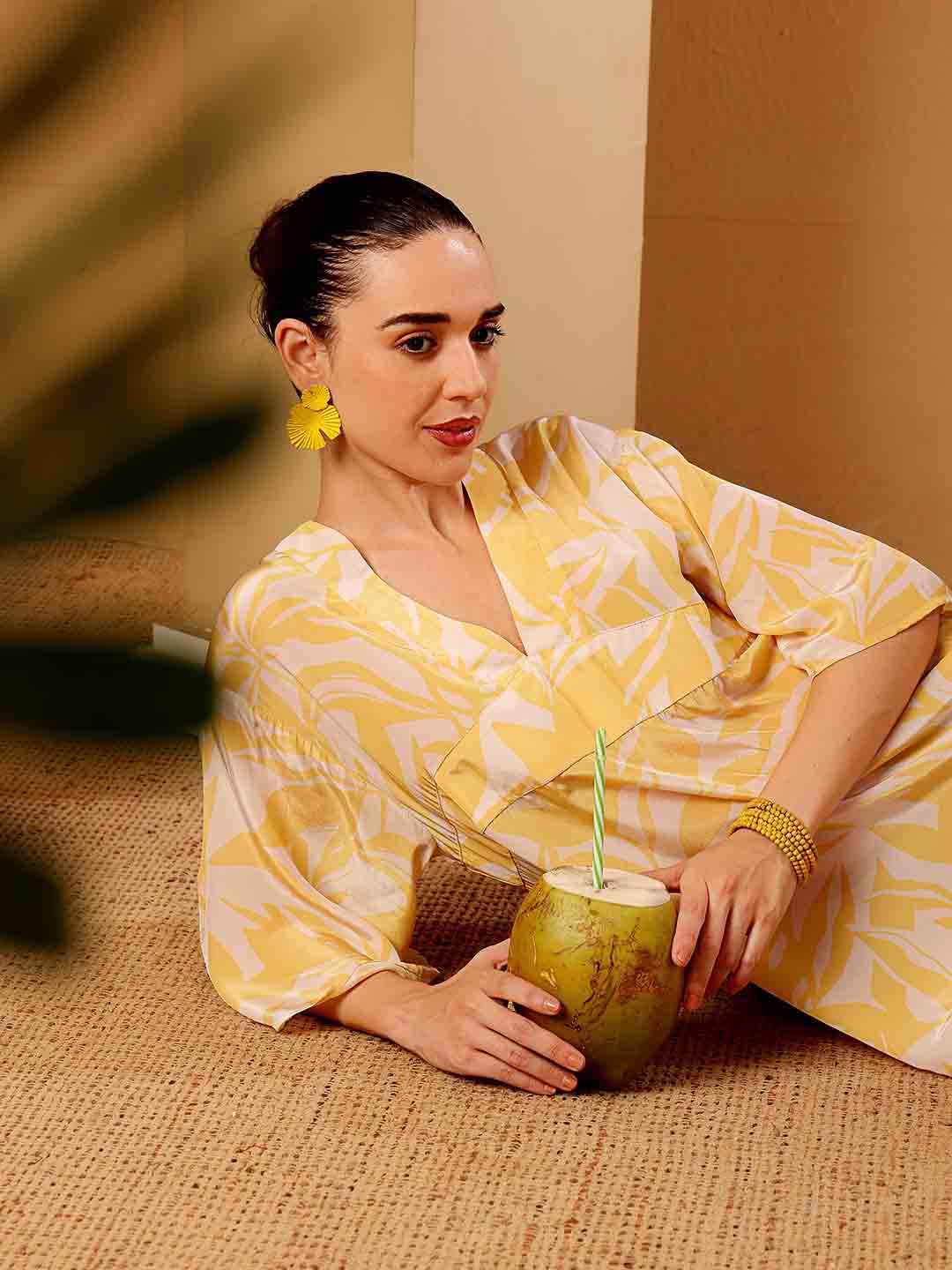 Stylized campaign shot of Model relaxing in Yellow printed floral beach coverup in a scenic resort setting