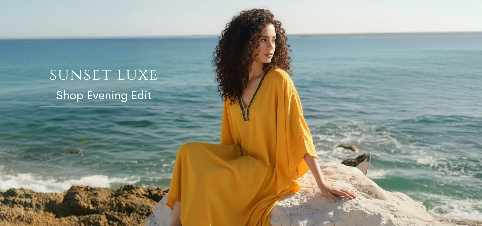 Woman in a yellow dress sitting on rocks by the ocean with 'Sunset Luxe' branding.