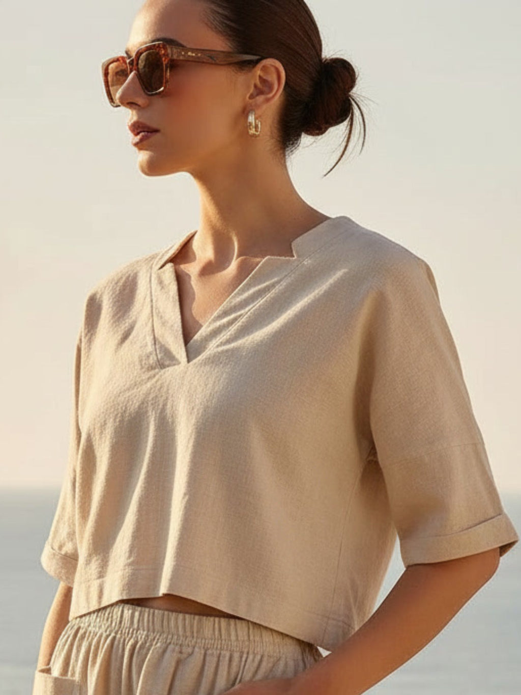 Woman wearing a beige co-ord set and sunglasses with a blurred background