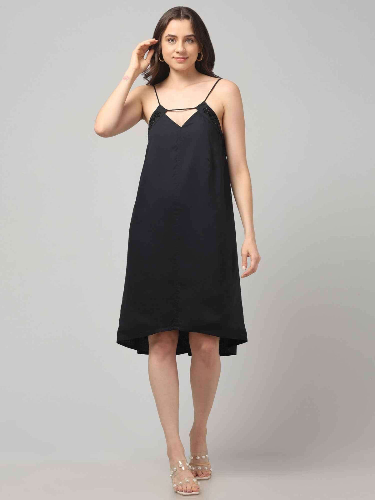 Women wearing a black resort wear cocktail dress with noodle strap and black embellishment on neckline