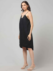 Side Profile of a women wearing a black resort wear cocktail dress with noodle strap and black embellishment on neckline