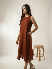 Side profile of a women wearing a copper summer resort dress with bird embroidery and high low hemline