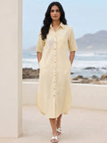 Woman in a cotton linen blend yellow shirt dress with embroidery walking with her hands in pocket.