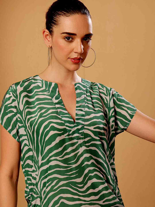Stylized campaign shot of Green animal print beach coverup in a scenic resort setting

