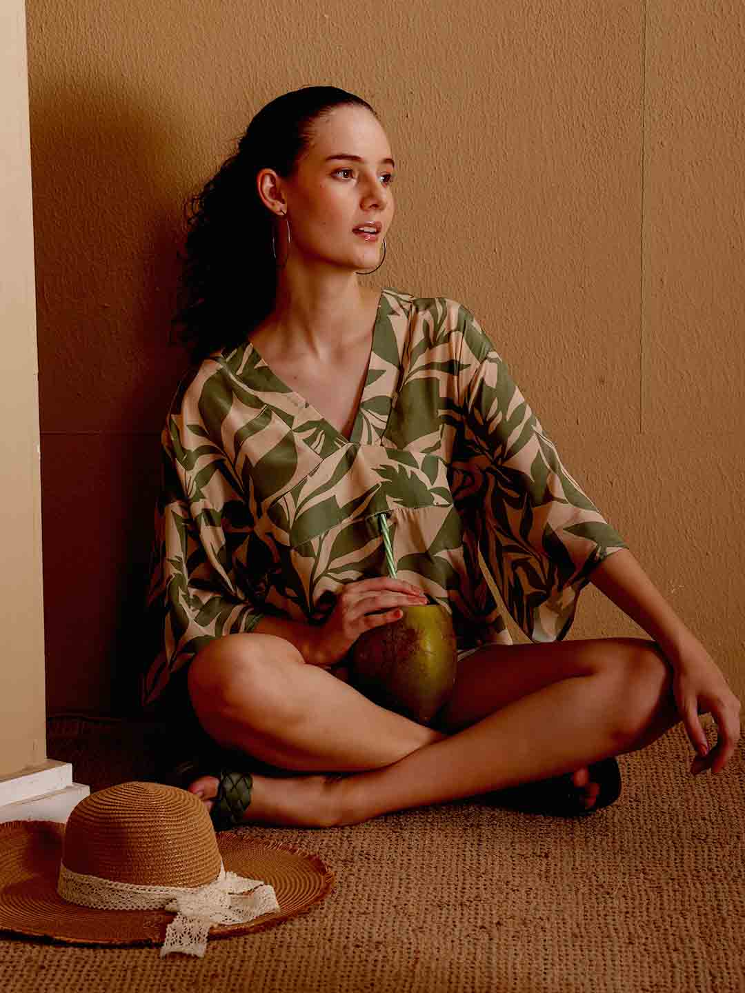 Stylized campaign shot of Model wearing Green printed beach coverup in a scenic resort setting
