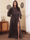 front pose of a Woman wearing a brown co-ord set with crop top and Skirt with Slit in a room with decorative elements.