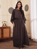 Woman wearing a brown co-ord set with crop top and Skirt with Slit in a room with decorative elements.
