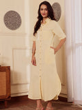 Woman wearing a light yellow cotton linen shirt dress with one hand in pocket