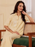 Woman wearing a light yellow cotton linen shirt dress sitting on a bench
