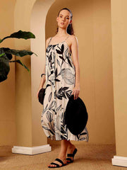 Stylized campaign shot of tropical printed resort maxi dress in a scenic resort setting
