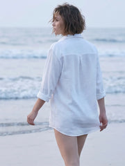 back profile shot of a women wearing white linen blend beach shirt with embroidery and walking on the beach