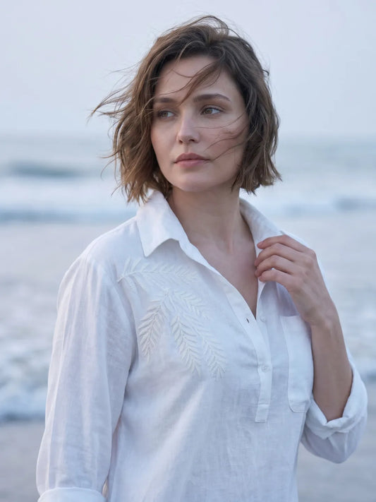 close up shot of a women wearing white linen blend beach shirt with embroidery and walking on the beach