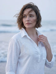 close up shot of a women wearing white linen blend beach shirt with embroidery and walking on the beach