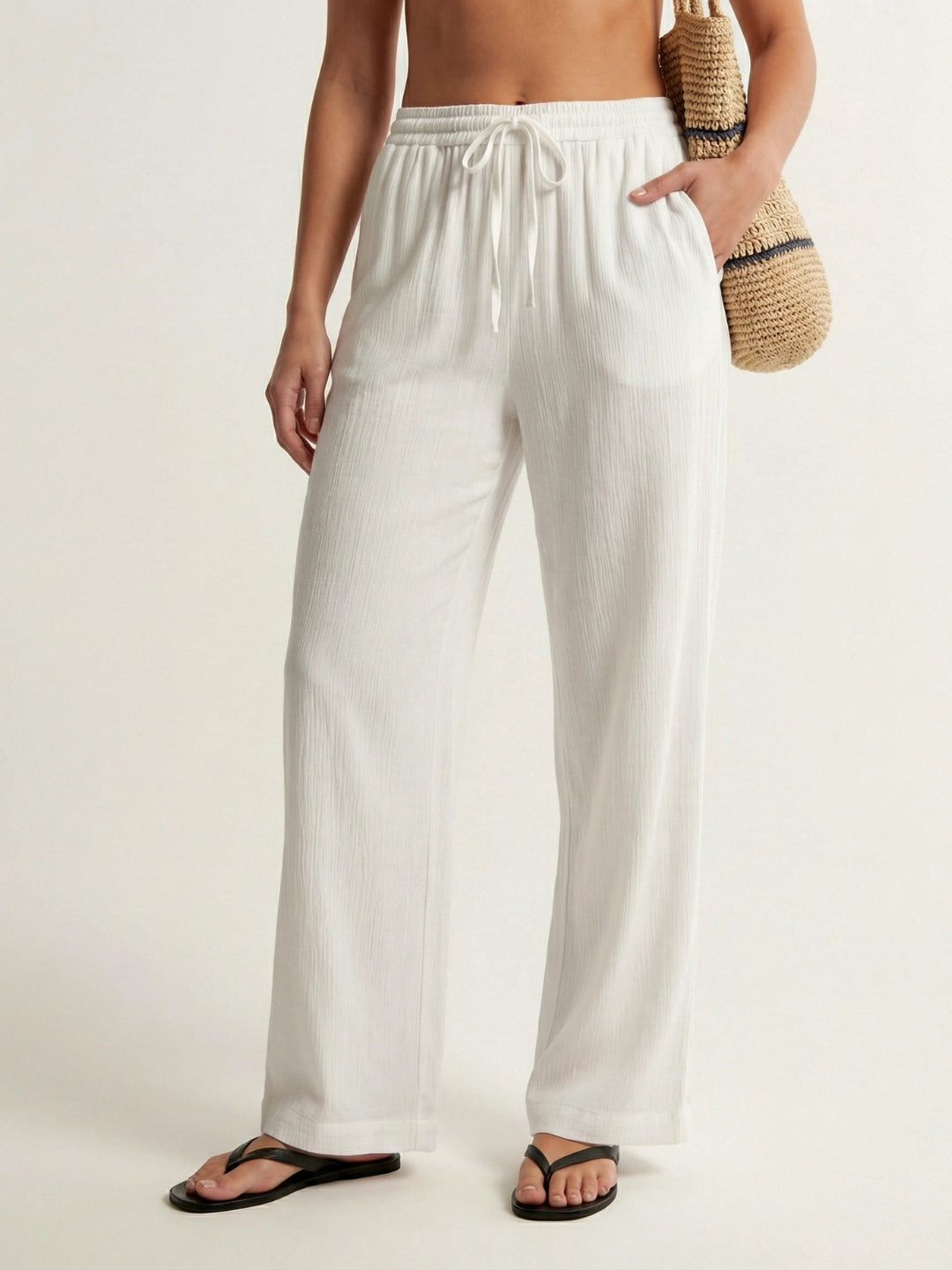 Person wearing white wide-leg pants on a plain background