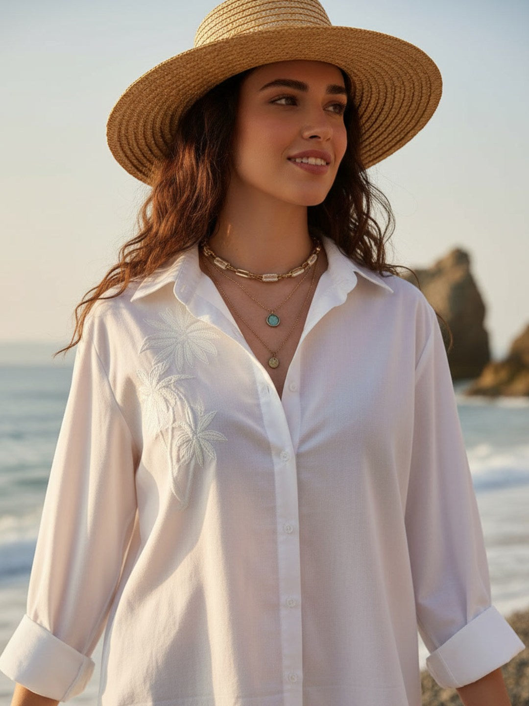 Woman wearing a white shirt and straw hat on a beach